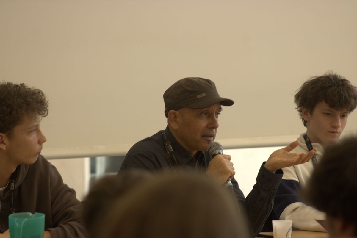 Gert-Peter Bruch parle au micro pendant un échange avec des élèves réunis autour d’une table.